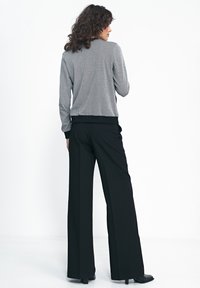 Szara bomberka w wzory z czarnymi ściankami mankietów, dopasowana do czarnych, szerokich spodni z wysokim stanem. Gładki materiał i luźny krój.