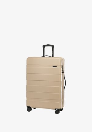 Maleta rígida de color beige con surcos horizontales, mango telescópico negro y cuatro ruedas negras para facilitar la maniobrabilidad. Cuenta con un asa lateral.