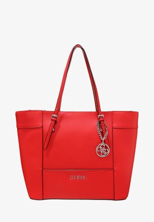 Czerwona torba typu tote Guess z podwójnymi paskami na ramię i srebrnym zawieszonym logo, zwisającym z jednego paska.