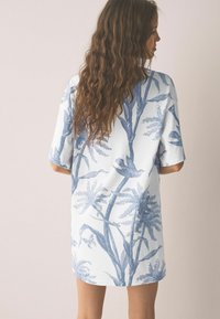 Helehall sinega lühikeste varrukatega kleit, millel on botaaniline muster üksikasjalike lehtede ja lindudega, valmistatud pehmest kangast, lõdva istuvusega.