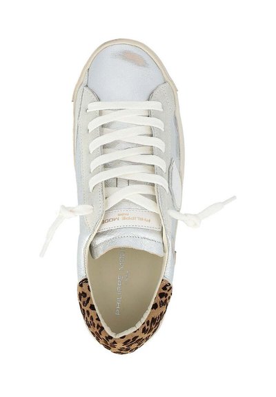 Zapatilla metálica blanca con cordones blancos y cuello trasero con estampado de leopardo, vista desde arriba, mostrando el nombre de la marca en el interior.