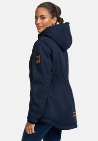 Navy hooded parka with elastic waist, side pockets, and decorative leather patch. Smooth material with a slightly shiny finish.