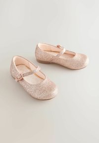 Rózsaarany csillogású Mary Jane cipők lapos talppal, kerek orral és szív alakú csattal ellátott pánttal. Puha belső bélés.