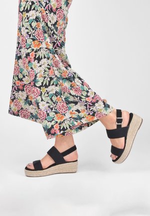 Sorte espadrille-sandaler med brede elastiske stropper og en vævet jute-mellemsål, med en spænde detalje på ankelsstroppen.