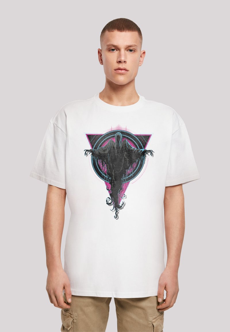 Bílý bavlněný tričko s výrazným grafickým designem postavy s roztaženýma rukama, umístěné na barevném geometrickém pozadí.