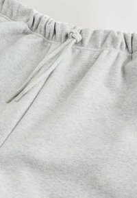 Light gray sweatpants with an elastic waistband and a tied drawstring detail at the front.
