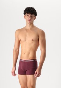 Bordauxfarbene Boxershorts aus weichem Stoff mit einem weißen Markenbund. Das Design hat eine enge Passform und eine glatte Textur.