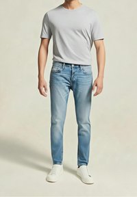 Vaaleanharmaa T-paita, siniset farkut haalistuneella viimeistelyllä ja valkoiset tennarit. Rentoon tyyliin suunniteltu arkiasu, jossa on yksinkertainen muotoilu ja väljä istuvuus.