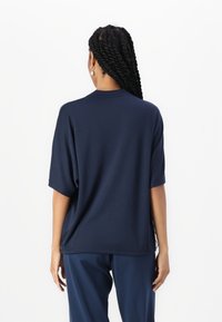 Marineblå oversized t-skjorte laget av et glat stoff med korte ermer og rund hals, sammen med matchende bukser.