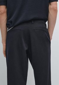 Marinebroeken van een gestructureerde stof, met twee achterzakken en een rechte voorkant. De tailleband is aansluitend en biedt een op maat gemaakte uitstraling.