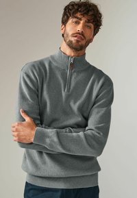 Szara bluza rozpinana z wysokim kołnierzem, prążkowanymi mankietami i dołem. Teksturowany materiał o gładkim wykończeniu. Minimalistyczny design.