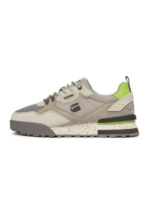 Niskie sneakersy w kolorze beżowo-szarym z siateczką i zamszem, zielony akcent na pięcie, masywna cętkowana podeszwa oraz czarna pętelka z tyłu.