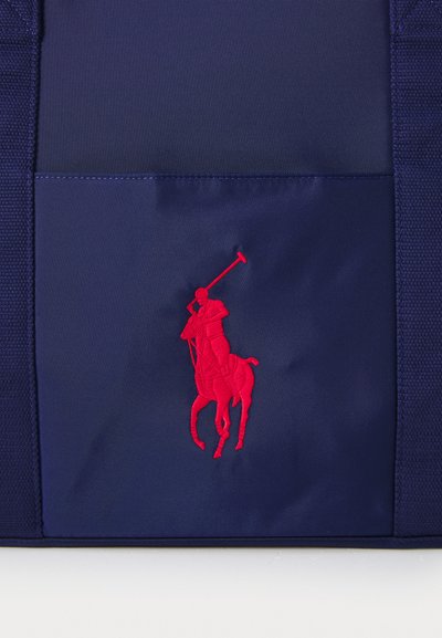 Navy blue nylon tote with a red embroidered polo logo. Features a textured surface and sturdy straps. Compact design with a side pocket.
