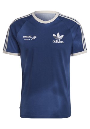 T-shirt Adidas bleu avec bordure et logo blancs, associé à un pantalon beige. Le mannequin porte des baskets blanches avec des rayures bleu marine et des accents beige.