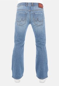 Vaqueros de denim azul acampanados con un lavado claro, que cuentan con dos bolsillos traseros con acentos de costura y una etiqueta de cuero marrón en la cinturilla.