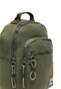 Maslinasto zelena ruksak napravljen od teksturiranog najlona, s dva zippered džepa, ručkom na vrhu i suptilnim brendiranjem sprijeda.