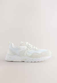 Baskets blanches de sport avec des panneaux en mesh et en suède, semelle épaisse tachetée et fermeture à lacets, vues de côté gauche sur un fond neutre.