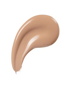 Un trait de fond de teint crémeux dans une teinte beige chaud, texture lisse avec un fini brillant, appliqué en forme courbe sur un fond blanc.