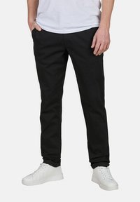 Schwarze Slim-Fit-Hosen aus Baumwollmischung mit glattem Griff. Verfügt über Seitenfächer und einen klassischen Stil, kombiniert mit weißen Sneakers.