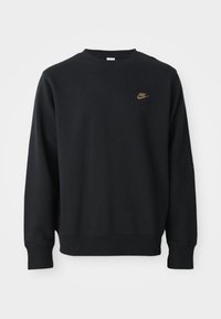 Čierna mikina vyrobená z jemnej tkaniny, s okrúhlym výstrihom, dlhými rukávmi a malým zlatým logom Nike na hrudi.