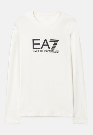 Ilgi piedurkņu kokvilnas T-krekls krēmkrāsā ar melnu EA7 Emporio Armani logotipa tekstu. Apaļš kakls un standarta fit ar taisnu apakšmalu. Mīksta tekstūra.