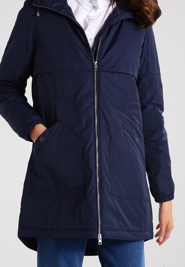 Chaqueta aislante azul marino con cremallera frontal, capucha y dos bolsillos frontales. Cuenta con puños elásticos y una longitud que llega hasta la mitad del muslo.