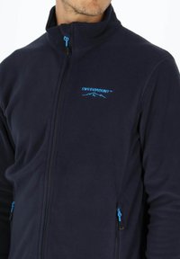 Marineblaue Fleecejacke mit hohem Kragen, durchgehendem Reißverschluss, blauen Akzenten und zwei seitlichen Reißverschlusstaschen. Mit 'SWEDEMOUNT™'-Logo auf der Brust.