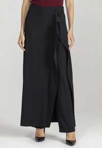 Czarna spódnica kopertowa z lekkiego, lejącego się materiału, z wiązaniem po boku i warstwowym fasonem. Długość sięga do kostek, a tkanina ma gładką fakturę.