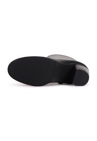 Bottine noire en cuir vue par la semelle, avec un petit talon bloc et une surface inférieure lisse et texturée.