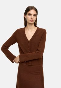 Brązowy, teksturowany kardigan z dzianiny z dekoltem w kształcie litery V i zapięciem na guziki z przodu, w zestawie z dopasowaną spódnicą.