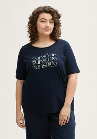 T-shirt à manches courtes marine avec un col rond et un design de texte "soleil" en vert clair et blanc. Tissu doux et lisse avec une coupe décontractée.
