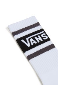 Calcetines Vans con textura acanalada, tela blanca con rayas negras y gris oscuro, y un distintivo parche de logo negro.