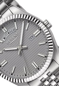 Montre en acier inoxydable argenté avec un cadran texturé, fenêtre de date à 3 heures, index polis et une lunette cannelée. Bracelet de style maillon.