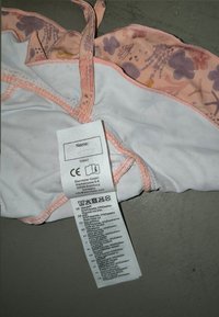 Pink and white fabric with floral pattern; includes care label sewn into the side. Features delicate stitching and adjustable straps.