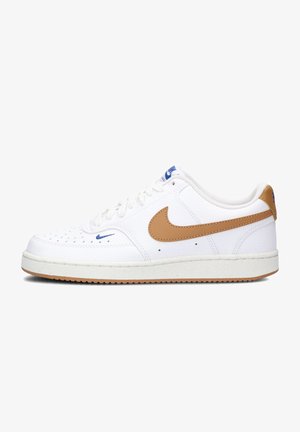 Sneaker bianco con una tomaia in pelle texturizzata, swoosh in pelle color nocciola e logo blu. Presenta perforazioni sulla punta e una suola in gomma.