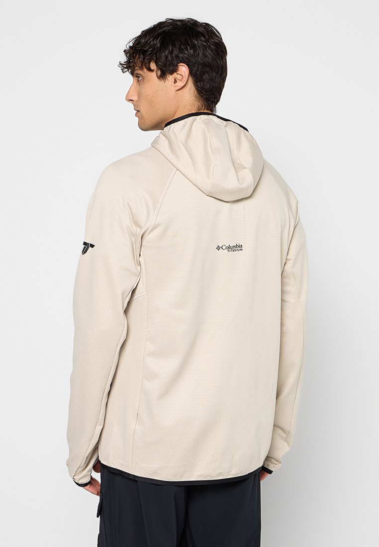Beżowa lekka kurtka z kapturem, z teksturowanej tkaniny i dopasowanym krojem. Posiada logo marki na plecach oraz akcenty na ramionach.