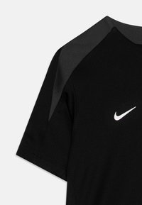 Must sportlik särg, millel on tekstuuriga viimistlus, halli õlaaktsendiga ja ees väike valge Nike'i logo.