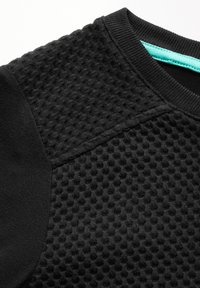 Musta tekstuurihuppari, jossa on kenno-kuvio vartalolla, litteät mustat hihat ja turkoosi yksityiskohta kaula-aukossa.