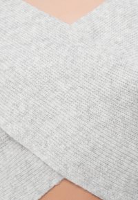 Szary, dziany materiał pokrywający skórzasty powierzchnię, z teksturowanym wzorem i dekoltem w kształcie litery V na środku.