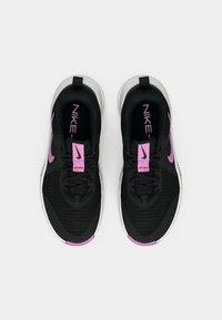 Melni sporta apavi ar teksturētu sietiņu augšdaļu, kontrastējošām rozā akcentēm un baltu zoli, ar logotipu un tekstu uz mēles.