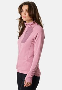 Veste zippée rose avec un col montant, tissu texturé, coupe slim et une poche poitrine avec un panneau contrastant. Manches longues avec des trous pour les pouces.