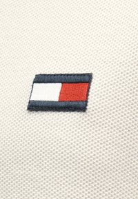 Ορθογώνιο υφασμάτινο ένθετο με ναυτικό μπλε περίγραμμα· διαθέτει μοτίβο με λευκά και κόκκινα τετράγωνα σε κρεμ υφή φόντου.