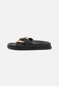 Black slide sandal featuring a woven strap with a knotted design and a gold accent. Smooth black sole with subtle texture for grip.