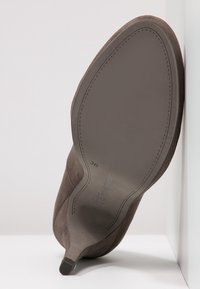 Brun mockaskosula, spetsig tå, med en slät kant och minimalistisk design. Storlek 36 tryckt på botten.