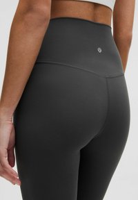 Mustat korkeat leggingsit, jotka on valmistettu sileästä, joustavasta kankaasta. Ominaisuuksina hienovarainen brodeeraus ja pieni logo takavöissä.