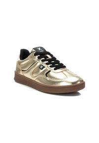 Zapatillas metálicas doradas con cierre de cordones negros, con una textura suave y una suela de goma marrón. Diseño de rayas sutil en el lateral.