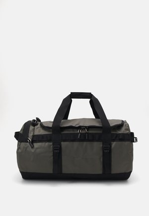 Duffel bag in dark green, made of durable material. Features black straps, clips, and a rounded shape with a zippered top.