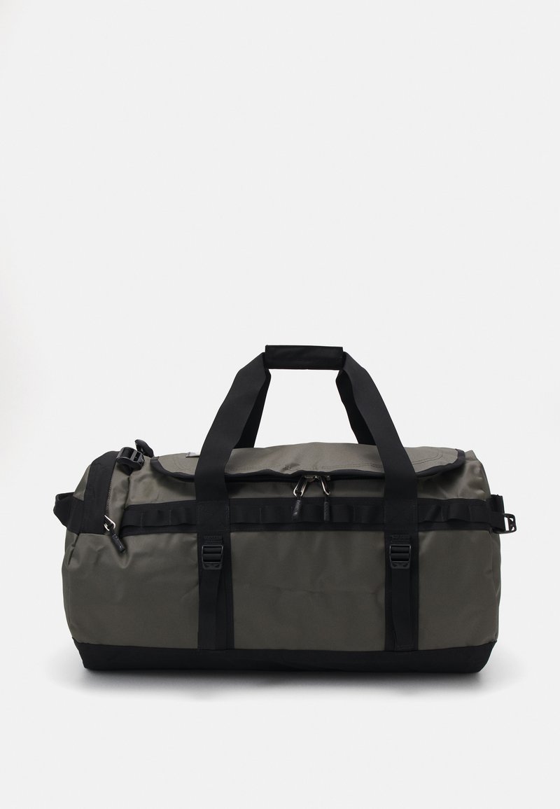 Sac de sport vert foncé, fabriqué en matériau durable. Dispose de sangles noires, de clips et d'une forme arrondie avec un dessus zippé.