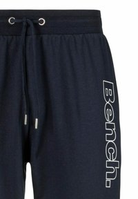 Marineblaue Jogginghosen aus weichem Baumwollmaterial mit einem elastischen Taillenband, ausgestattet mit einem Kordelzug und einem großen weißen "Bench."-Logo an der Seite.
