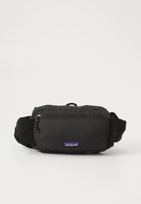 Schwarze Stoff-Wellness-Tasche mit einem Reißverschlussfach, verstellbaren Trägern und einem kleinen Patagonia-Logo-Patch auf der Vorderseite.